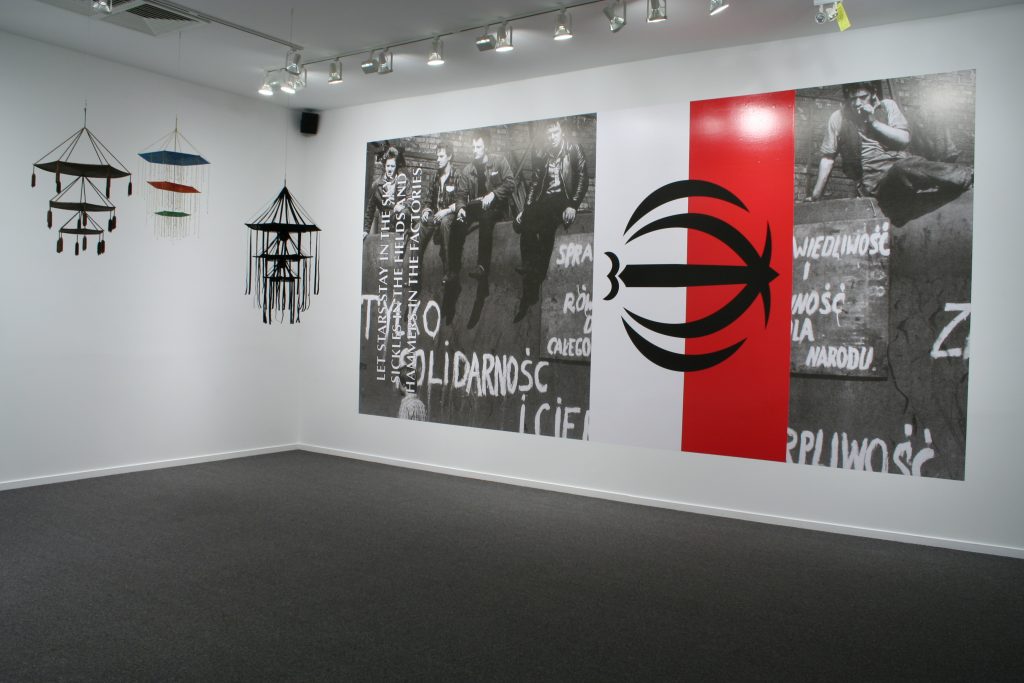 (L to R) Pajaki, 2011, variable materials, dimensions and Only Solidarity and Patience Will Secure Our Victory, 2010, print on vinyl, 3 x 6 m