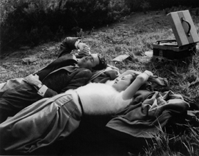 John Swope, Jimmy Stewart and Olivia de Havilland lying on grass, 1938, b/w photograph